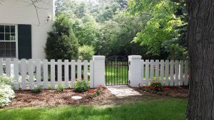 Dog-ear, wide picket fence with arch-top wrought iron metal gate