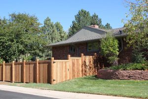 Wooden fencing, cedar privacy fence with wide access gate and decorative notched top 6 inch posts and cap rail