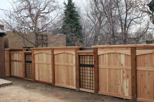 wood and metal fencing: privacy fence with metal trellis inserts and arched top and flat cap details.